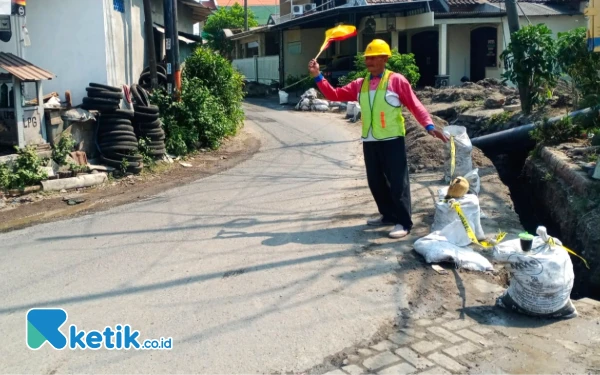 Foto Pekerja berjaga di jalan untuk menjaga keselamatan pengguna jalan dan pekerja proyek pemasangan JDU Perumda Delta Tirta. (Foto Annisah for Ketik.co.id)